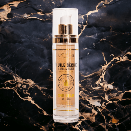 Flacon d'huile sèche précieuse pour visage, corps et cheveux, fond marbre noir et or, soin nourrissant et illuminant.