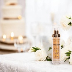 Huile sèche éclat visage, corps et cheveux, flacon élégant entouré de fleurs blanches et bougies, soin nourrissant et sublimant.